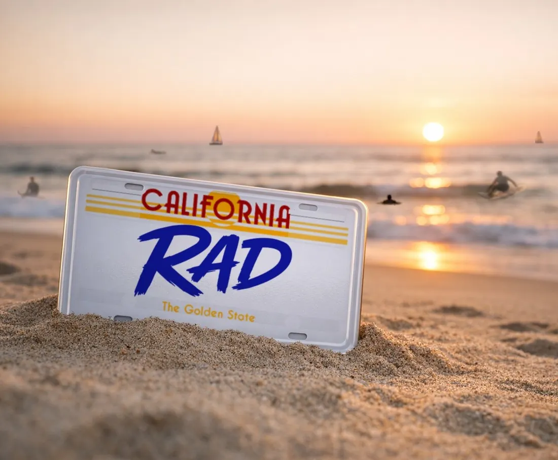 White California license plate reading RAD stuck in beach sand at sunset